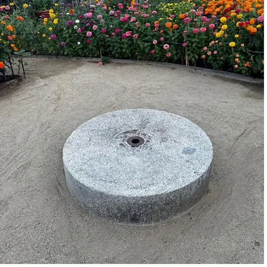 Antigua rueda de molino de piedra usada hoy como adorno en un jardín